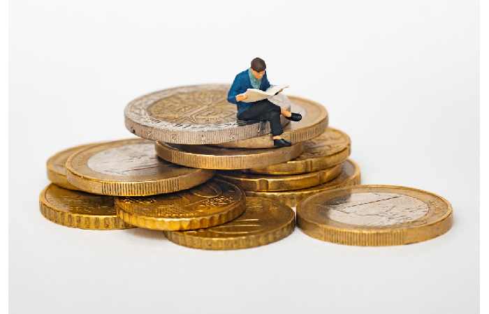 A figurine of a man seated atop a pile of coins, symbolizing financial success enabled by the best PSA software.