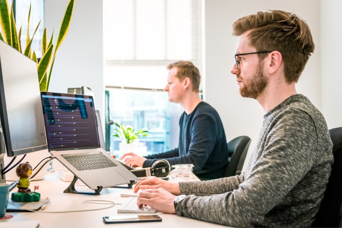 How Does Opportunity Management Software Work? 2 Two men focused on their work, sitting at computers in a professional office environment.