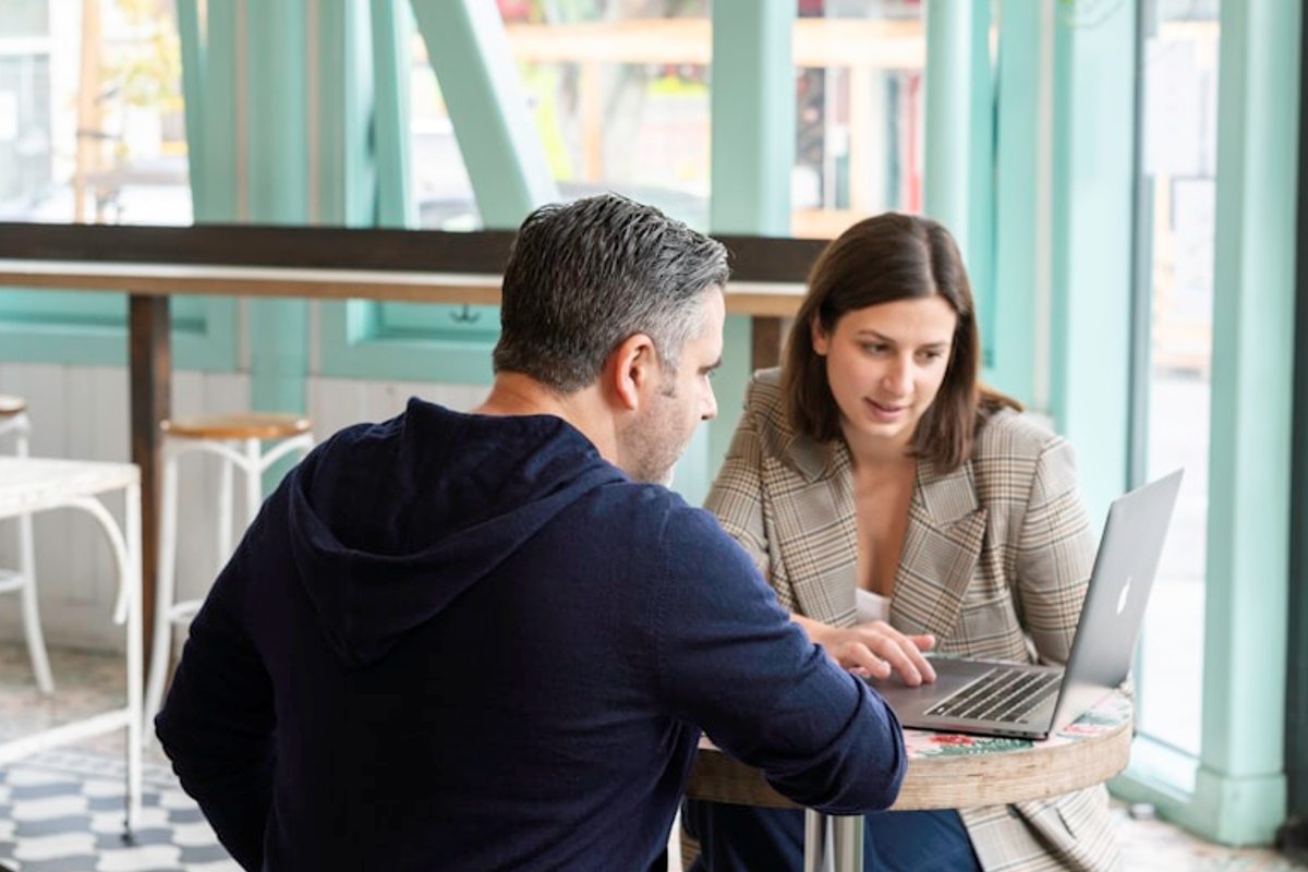 How Does Opportunity Management Software Work? 1 A man and woman sitting at a table with a laptop, discussing how opportunity management software works.